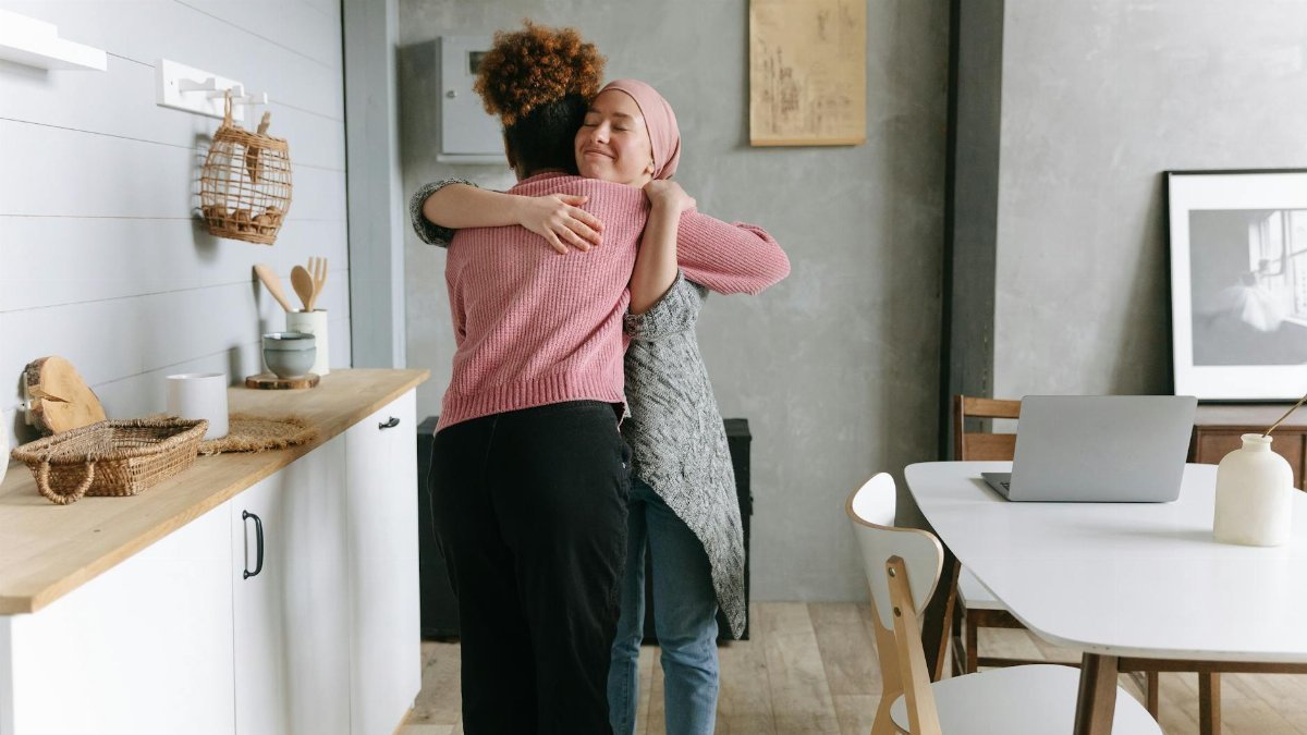 Two women embracing warmly indoors, symbolizing support and friendship.
