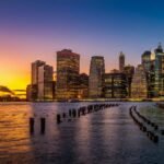 Breathtaking view of New York City's illuminated skyline during a vibrant sunset over the river.
