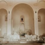 Interior of an abandoned church with crumbling altar and ruins, showcasing historical religious architecture.