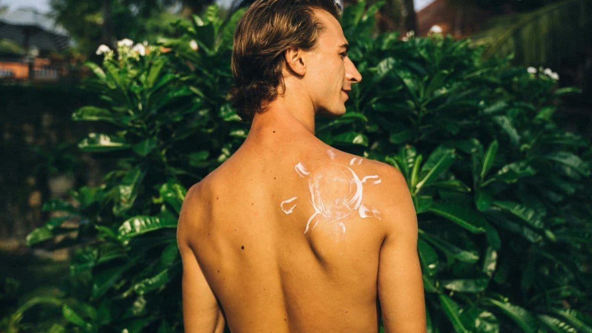 Back view of a shirtless man outdoors with a sun pattern on his shoulder.
