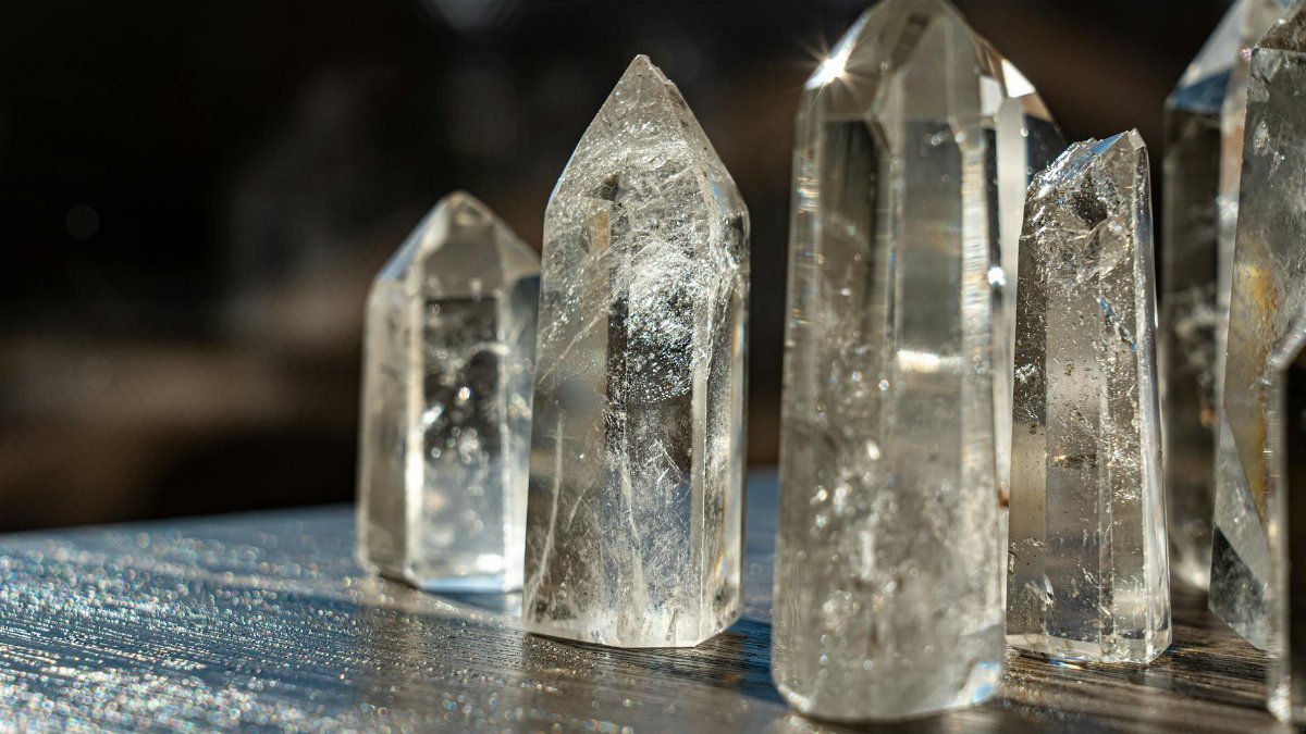 A detailed close-up of clear quartz crystals reflecting light with a blurred background.