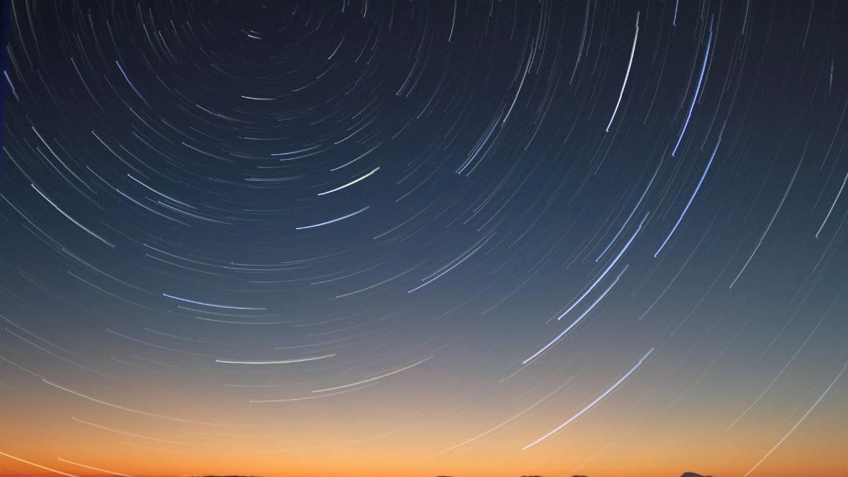 A stunning long exposure of star trails over the ocean horizon at twilight.
