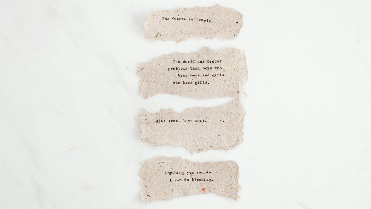 Collection of inspirational phrases on white paper scraps, emphasizing love and equality.
