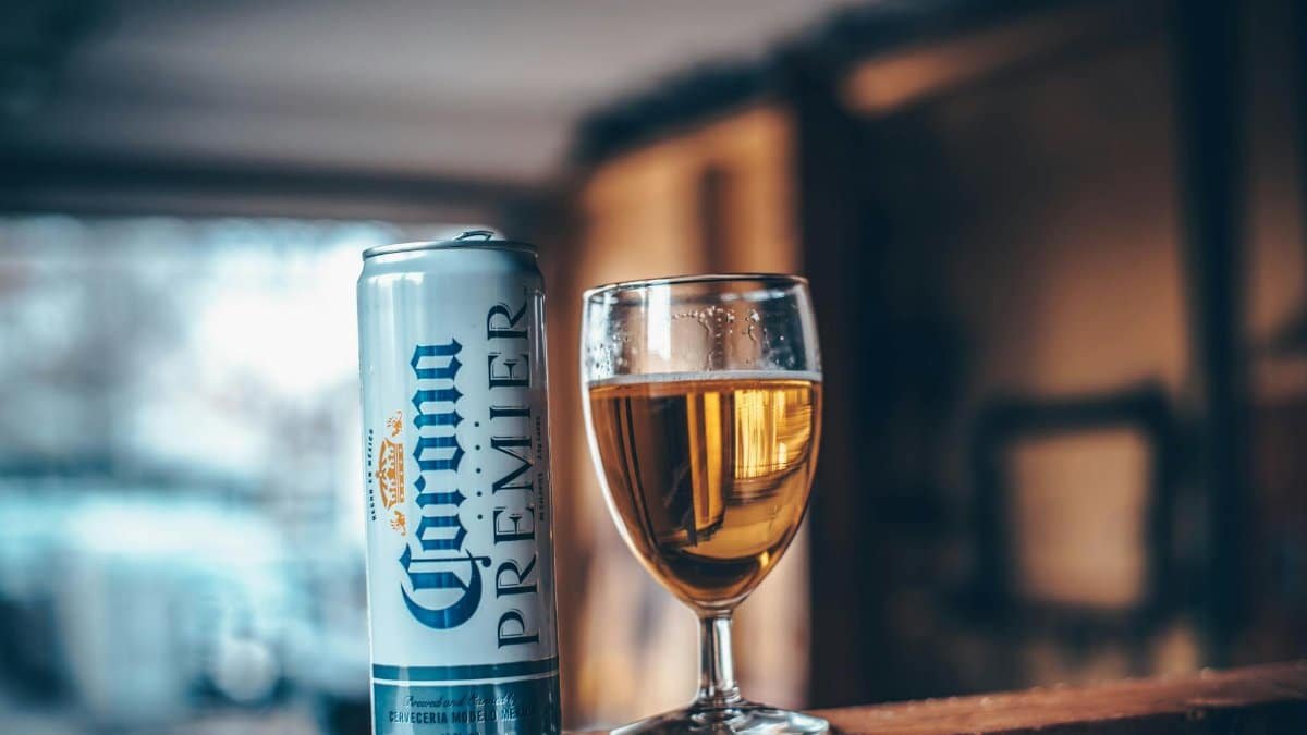 Close-up of a glass of beer and an aluminum can indoors with warm lighting.