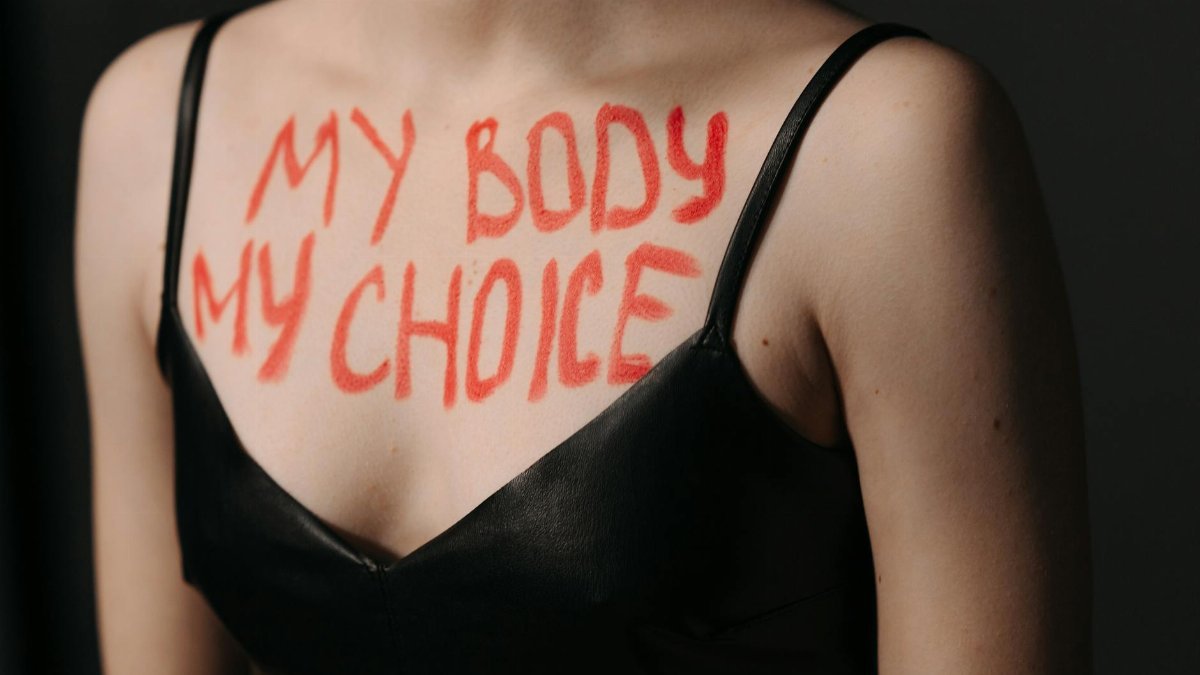 Close-up of empowering feminist slogan 'My Body My Choice' on woman's chest in black dress.