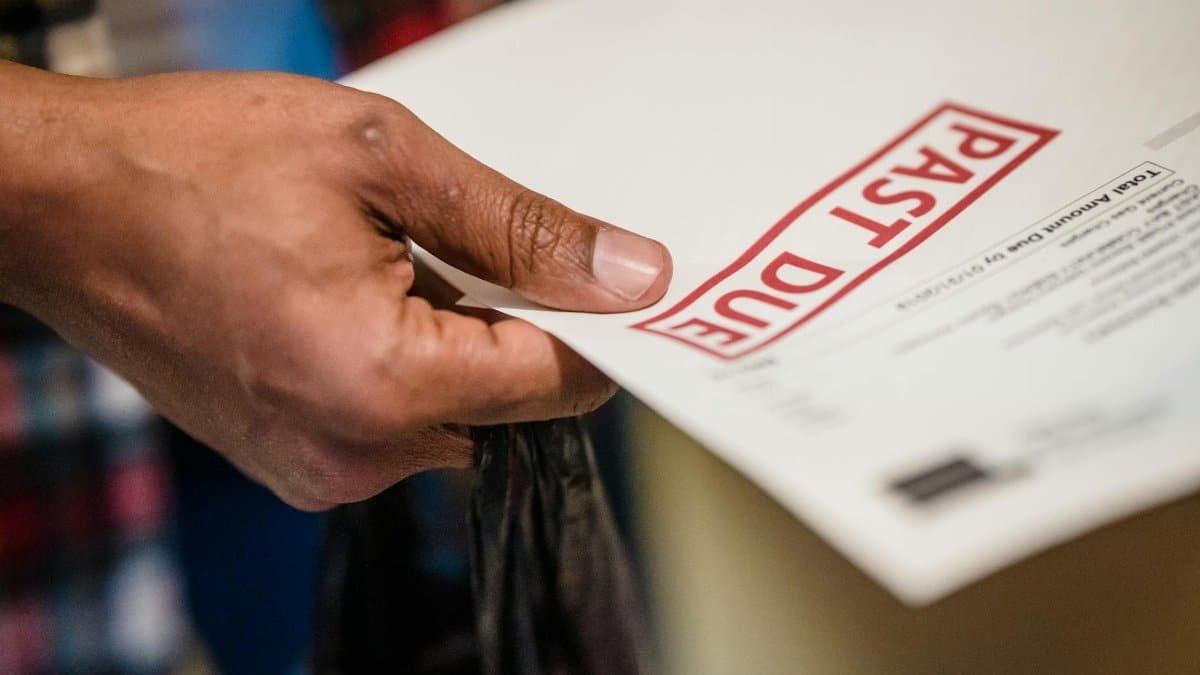 A close-up of a hand holding a document with a 'Past Due' stamp, highlighting financial urgency.