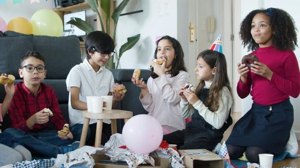 A lively indoor children's party featuring kids enjoying donuts and balloons. Perfect celebration vibes.