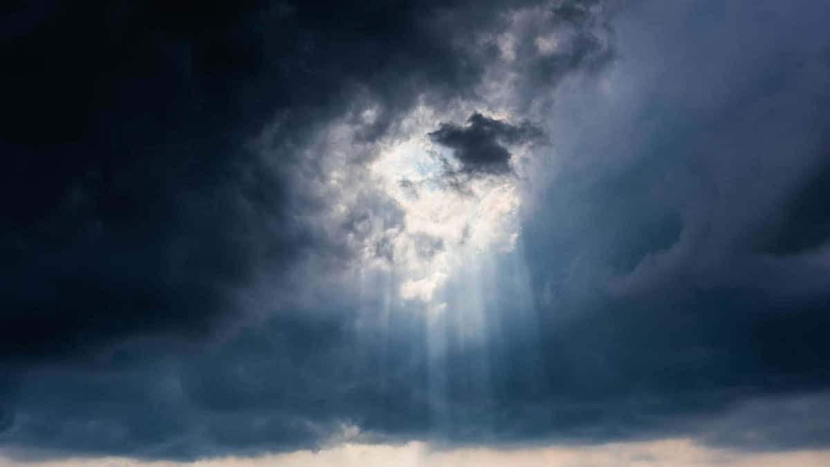 Dramatic sky with sun rays breaking through dark stormy clouds, creating a majestic view.