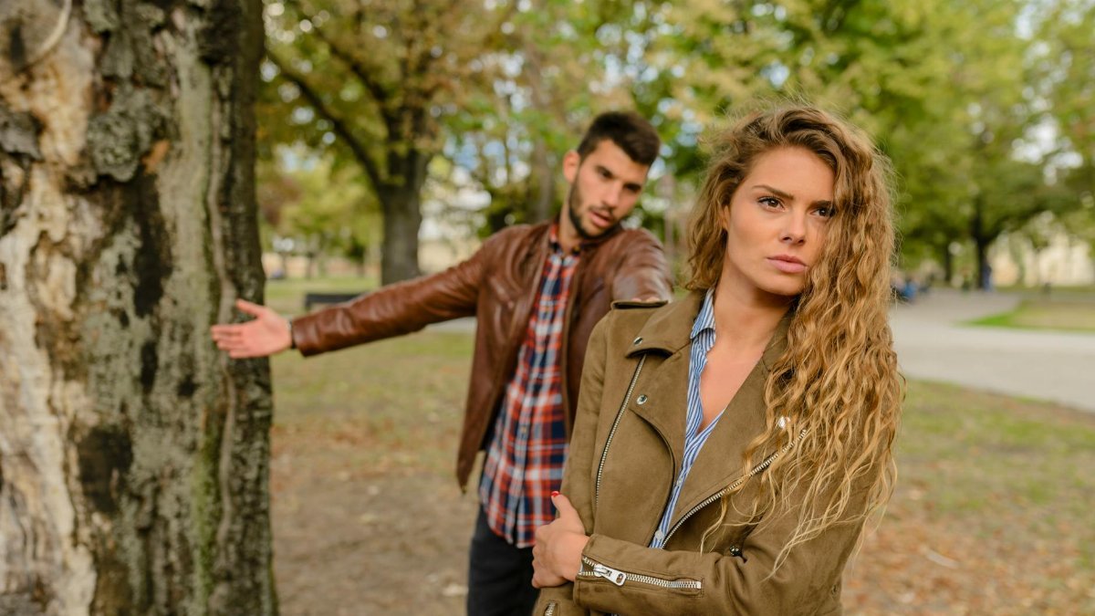 A man and woman in a heated argument outdoors, expressing emotions.