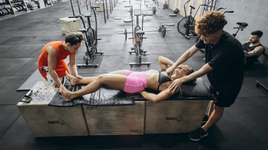 Athletes engage in recovery therapy with cupping and massage in a gym.