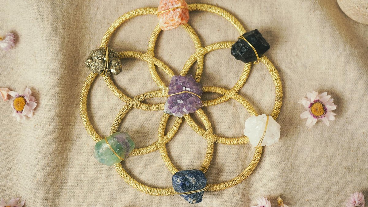 Vibrant crystal grid on fabric with healing stones and floral accents for meditation and energy enhancement.