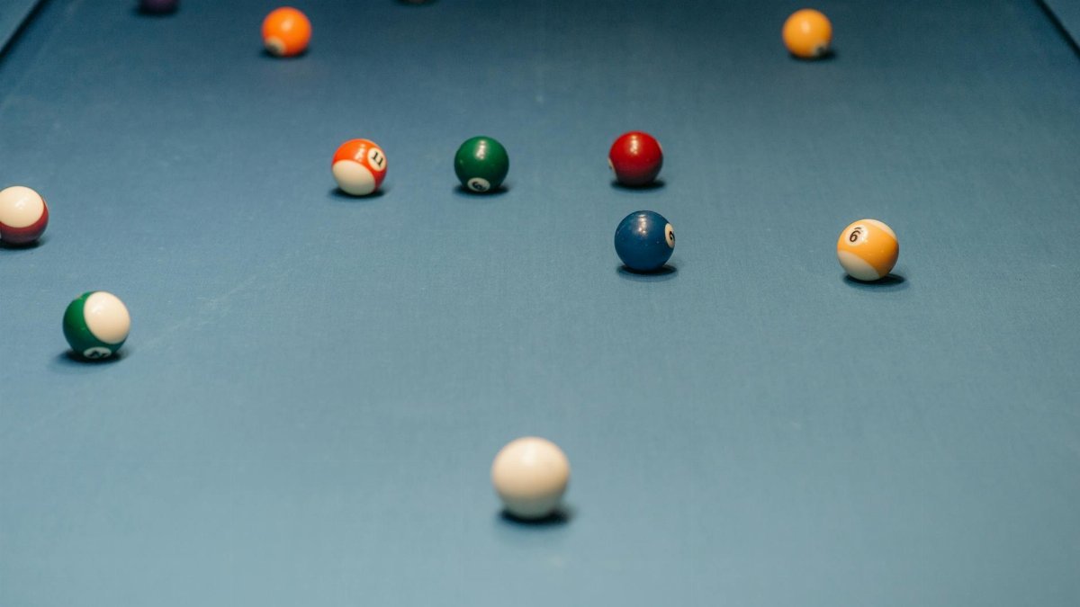 Vibrant billiard balls spread across a blue pool table, ready for a game.
