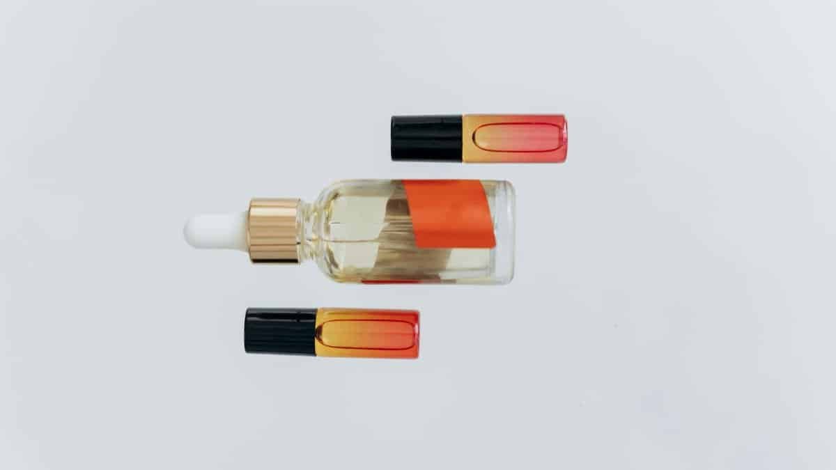 Minimalist flat lay of essential oil bottles with a pipette on a white background, perfect for wellness and beauty themes.