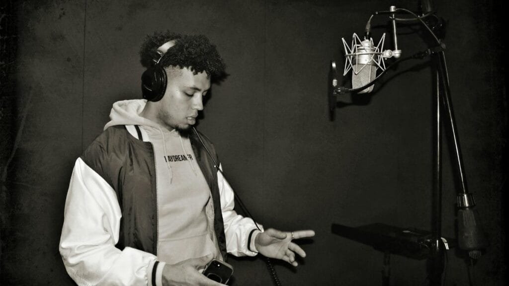 A focused young rapper performing in a professional recording studio.