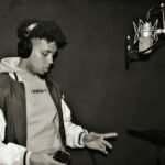 A focused young rapper performing in a professional recording studio.