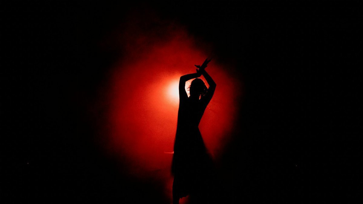 Captivating silhouette of a dancer performing gracefully with a dramatic red background.