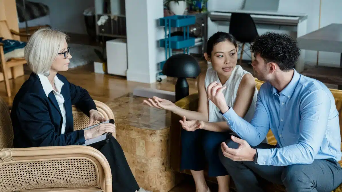 Couple having a discussion with a counselor in a modern living room setting.