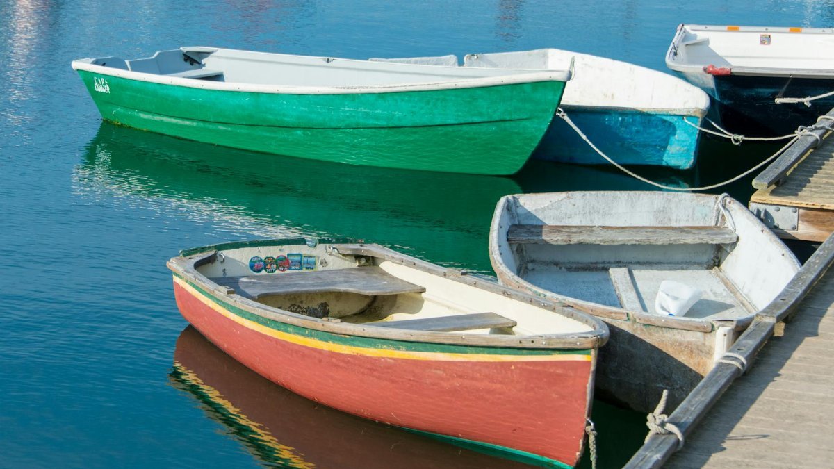 Vibrant rowboats moored at a pier in Newport, Rhode Island, reflecting on calm water.