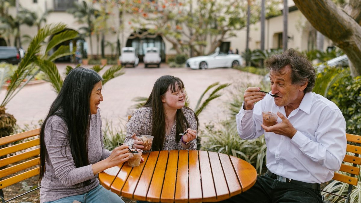 A joyful family enjoying desserts together outdoors at a wooden table, sharing smiles and love.