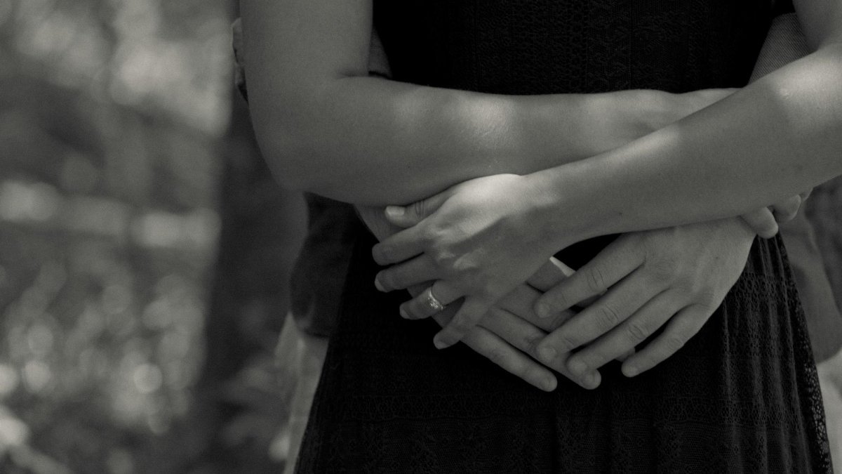 Close-up black and white photo of a couple hugging outdoors, capturing intimacy and love.