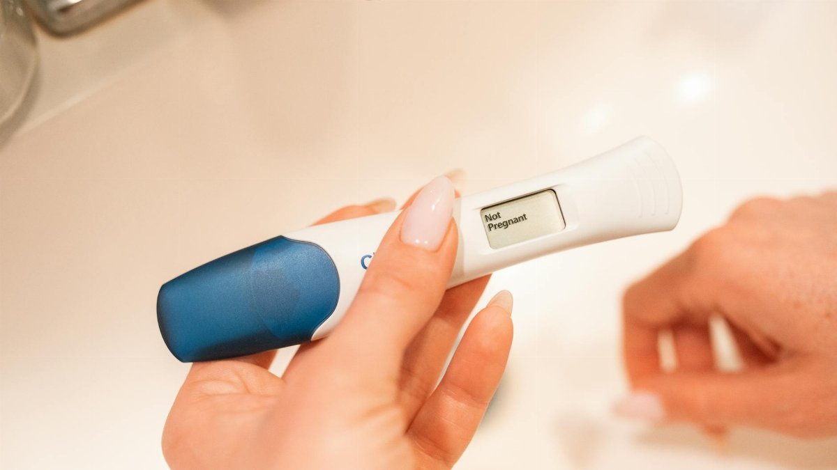 Close-up of a negative pregnancy test displayed by a woman's hand.