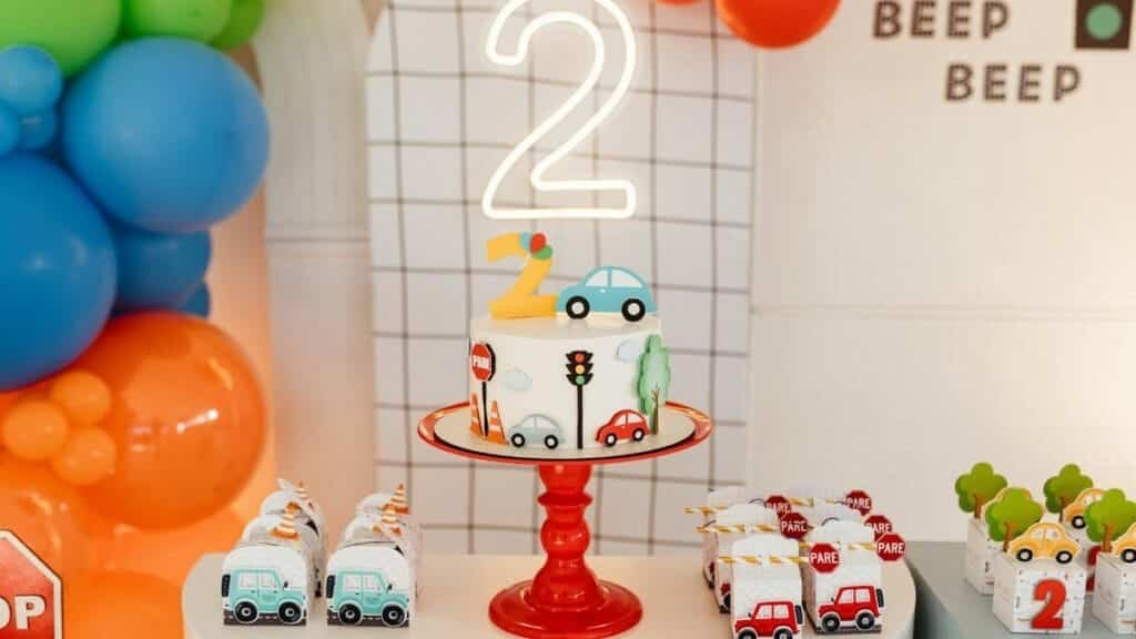 A vibrant birthday celebration setup with a traffic-themed cake and colorful balloons for a second birthday party.