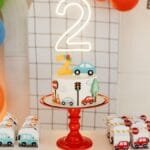 A vibrant birthday celebration setup with a traffic-themed cake and colorful balloons for a second birthday party.