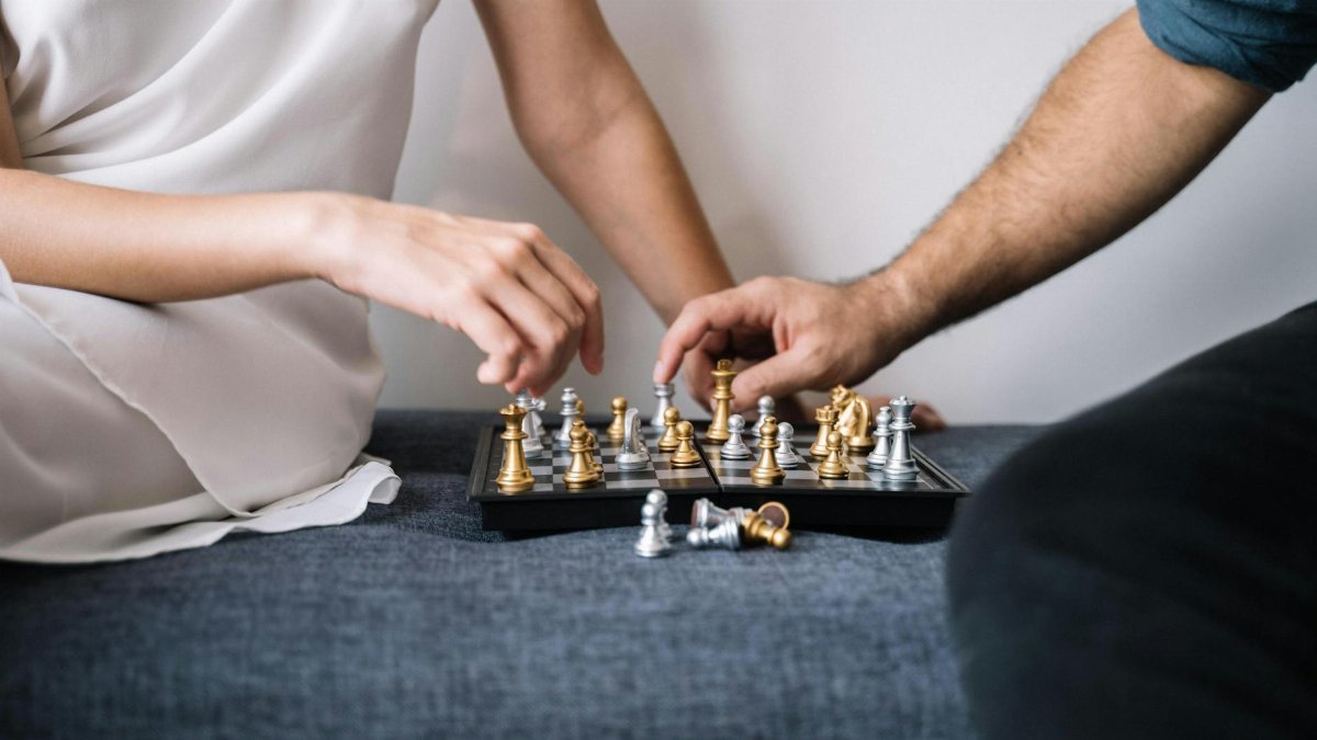 Close-up of two adults engaged in a strategic chess game indoors.
