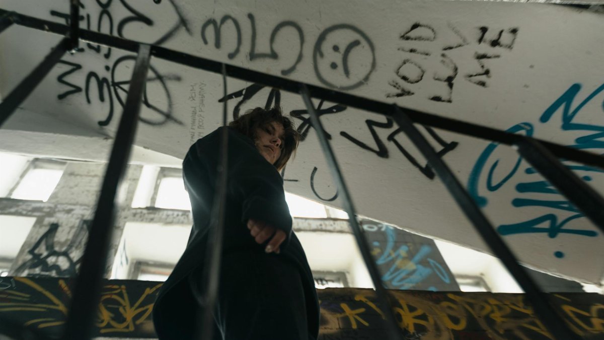 Teenager standing on a graffiti-covered staircase, embodying urban street art culture.