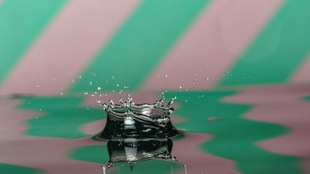 Dynamic close-up of a water splash against a colorful striped backdrop, showcasing abstract energy.