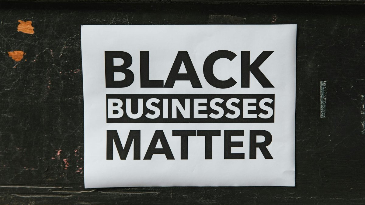A poster advocating support for Black-owned businesses displayed on a textured wall.