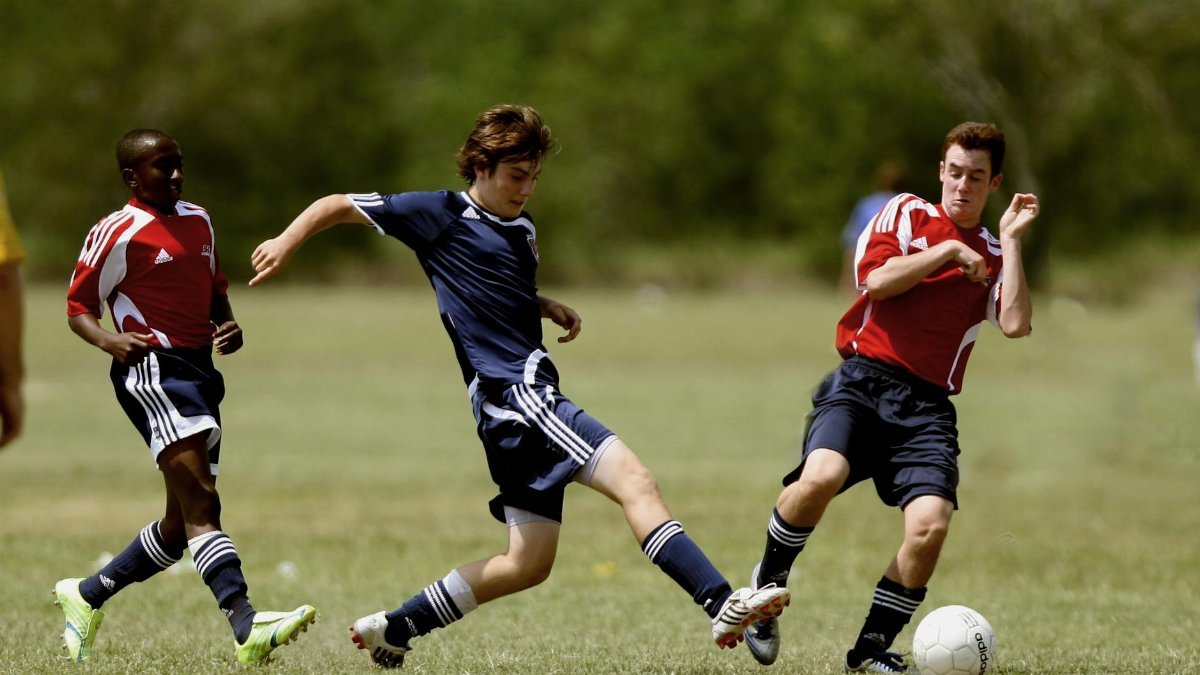 Teenage soccer players in action during an outdoor match showcasing skill and competition.