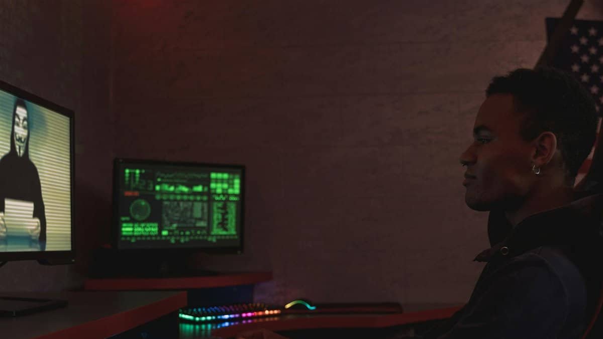 A cybersecurity professional monitors data systems in a dark room, emphasizing protection and vigilance.
