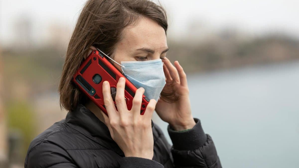 A person wearing a face mask makes a phone call, representing safety and connectivity.