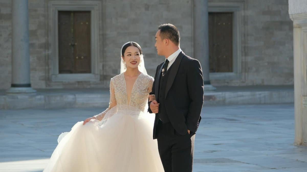 Bride and groom walking in a sunlit courtyard, expressing love and joy on their wedding day.