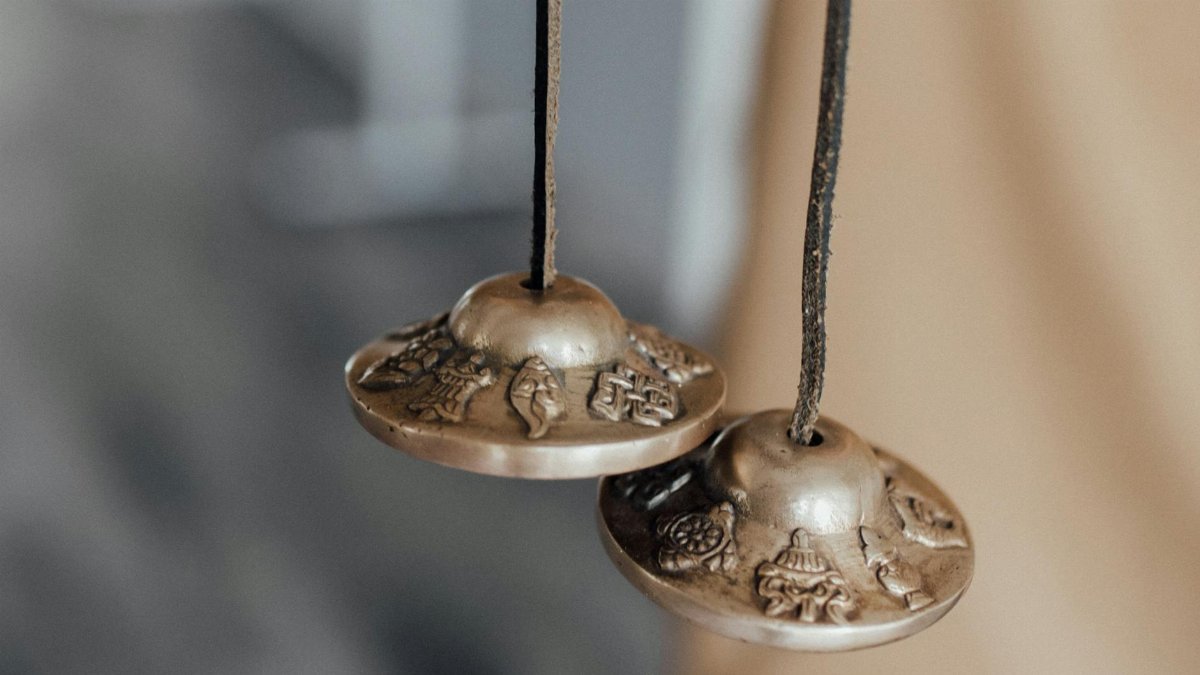 Detailed close-up of ornamented Tibetan tingsha bells used in spiritual practices.