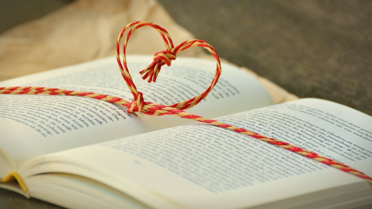 Open book with a heart-shaped string bookmark, symbolizing love for reading.