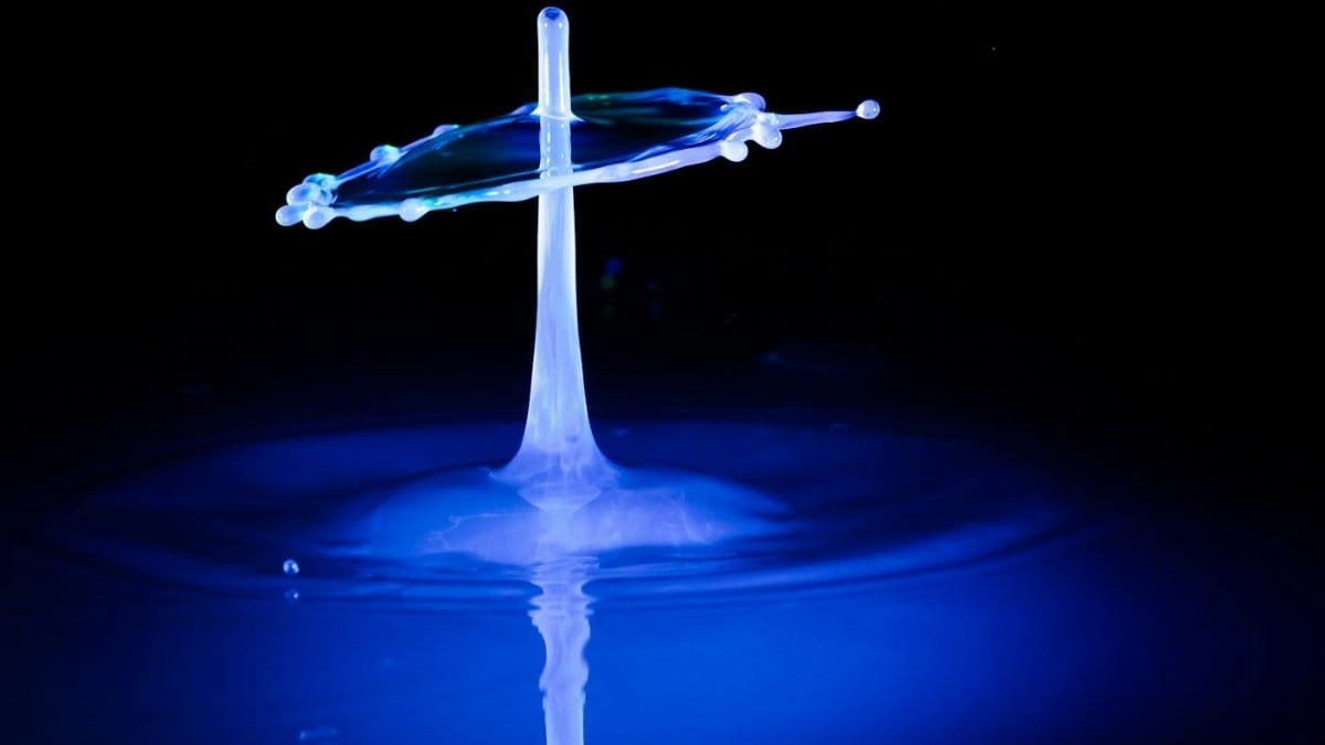 Captivating high-speed photograph of water drop collision under dramatic lighting, showcasing fluid dynamics.