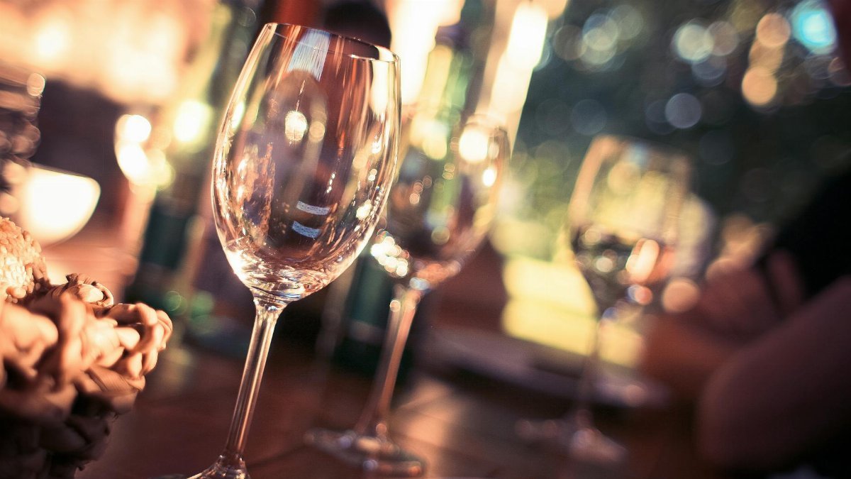 Close-up of wine glasses on a dining table with bokeh lights, creating a warm and inviting atmosphere.