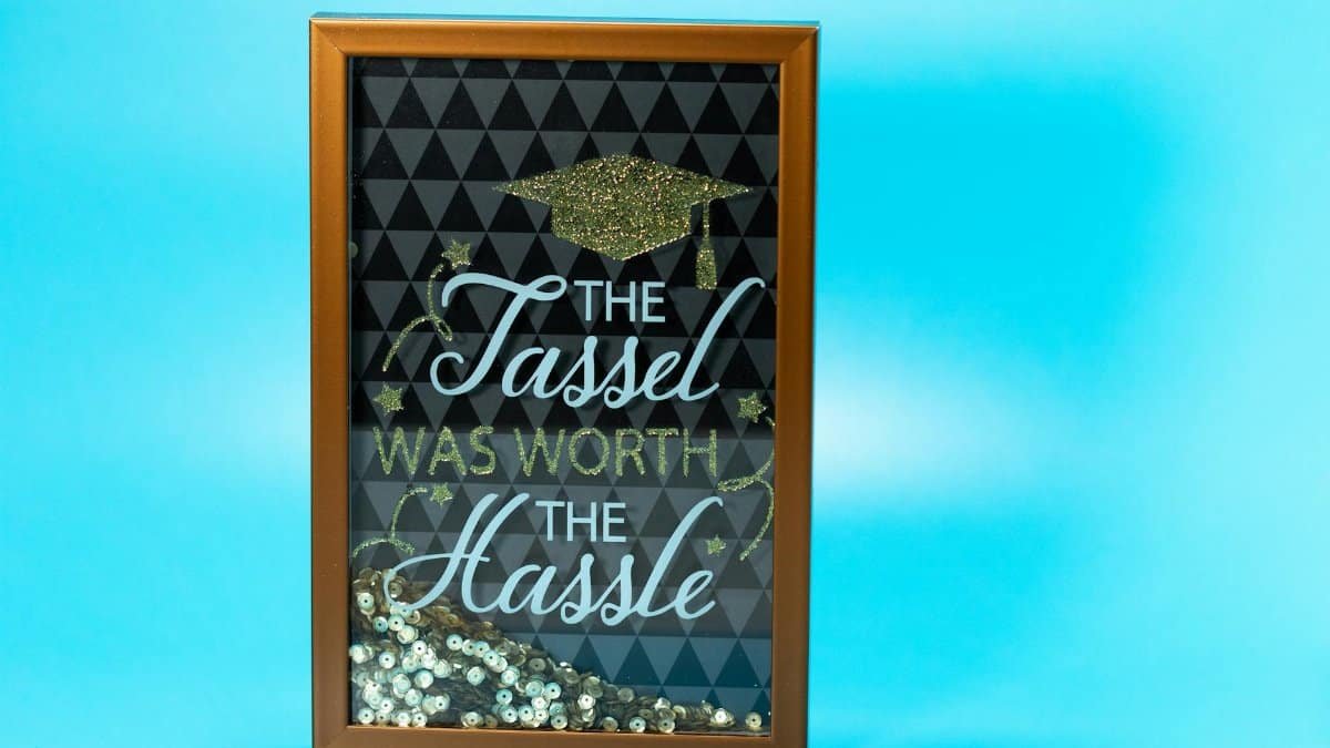 Framed quote 'The Tassel Was Worth The Hassle' on light blue background.