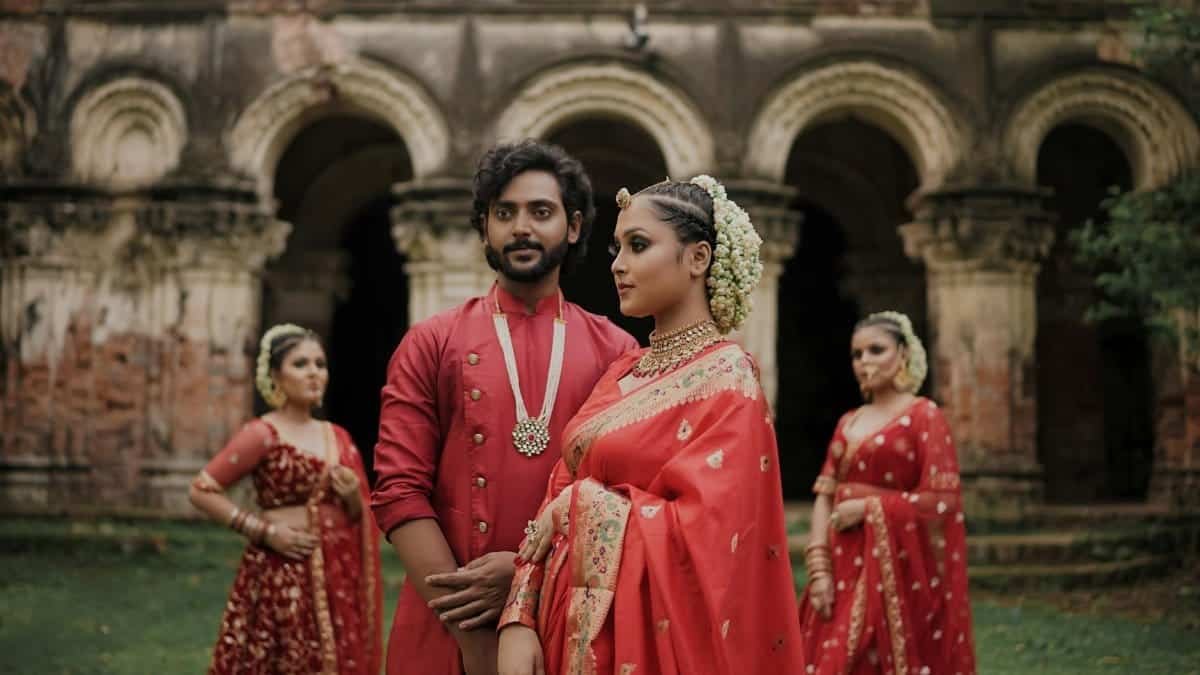 Group in traditional Indian wedding attire in front of historic architecture.