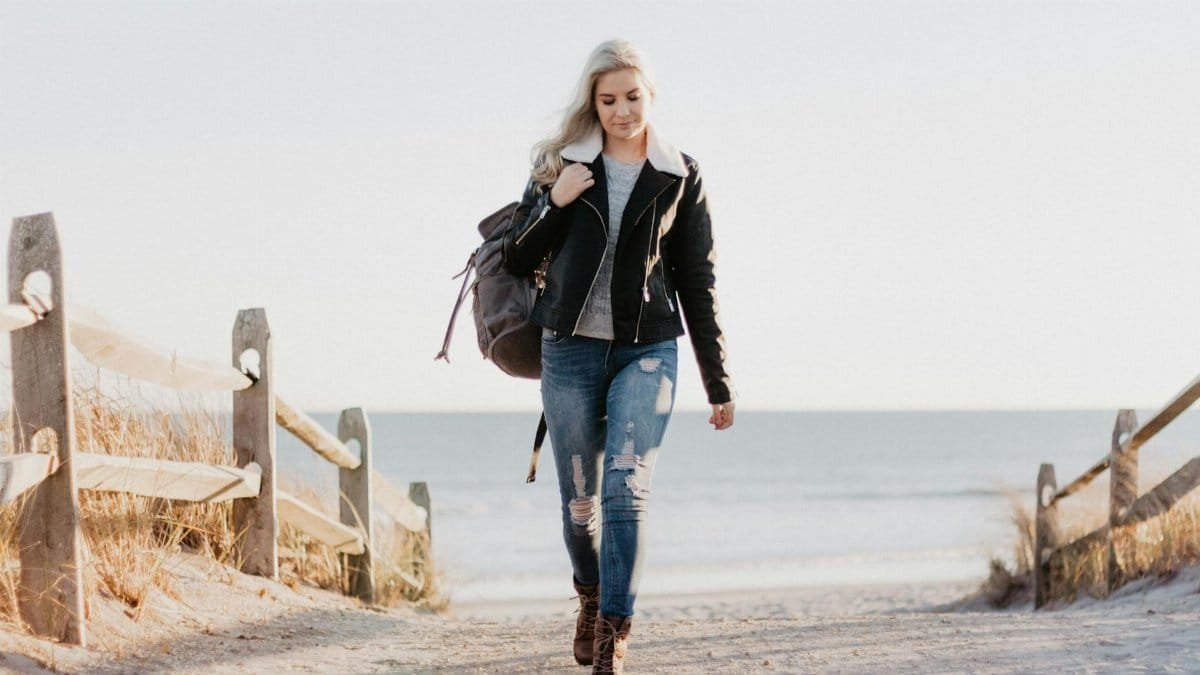 Stylish woman in leather jacket walking by the ocean in Ocean City, NJ.