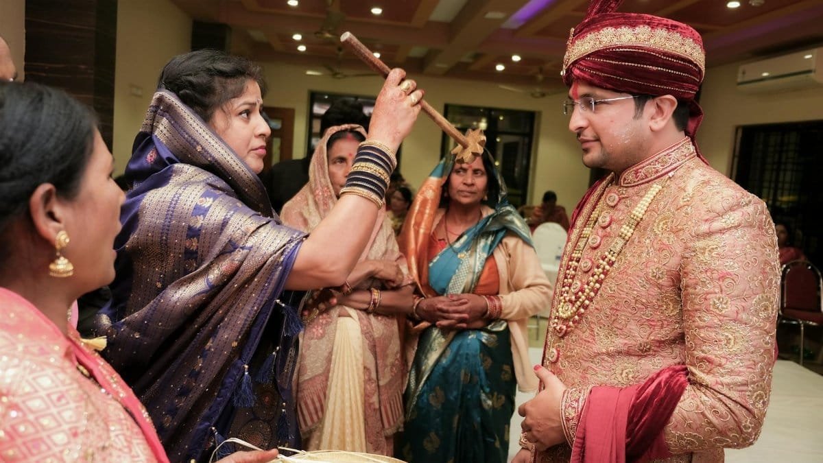 A traditional Indian wedding ceremony featuring a groom in elegant attire participating in a ritual.