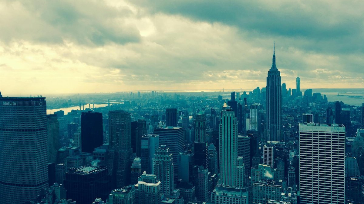 A breathtaking aerial view of New York City featuring the iconic Empire State Building under a dramatic sky.
