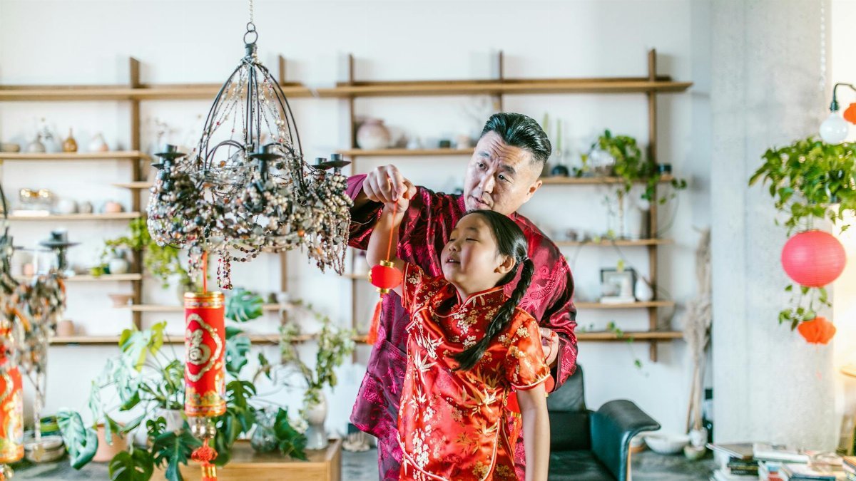 A joyful moment of a grandfather and granddaughter celebrating Chinese New Year with traditional decorations.