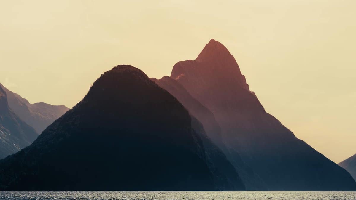 Dramatic sunset over Milford Sound, New Zealand, highlighting the majestic mountains and serene sea.