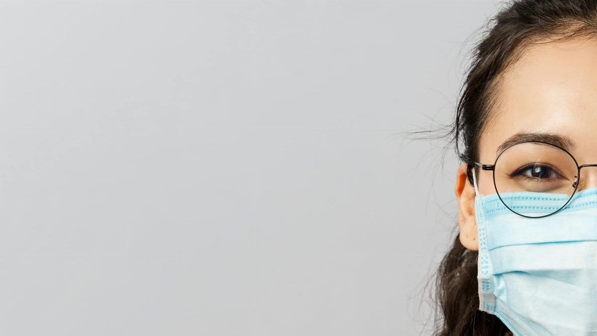 Close-up of a woman wearing glasses and a face mask, highlighting new normal trends.