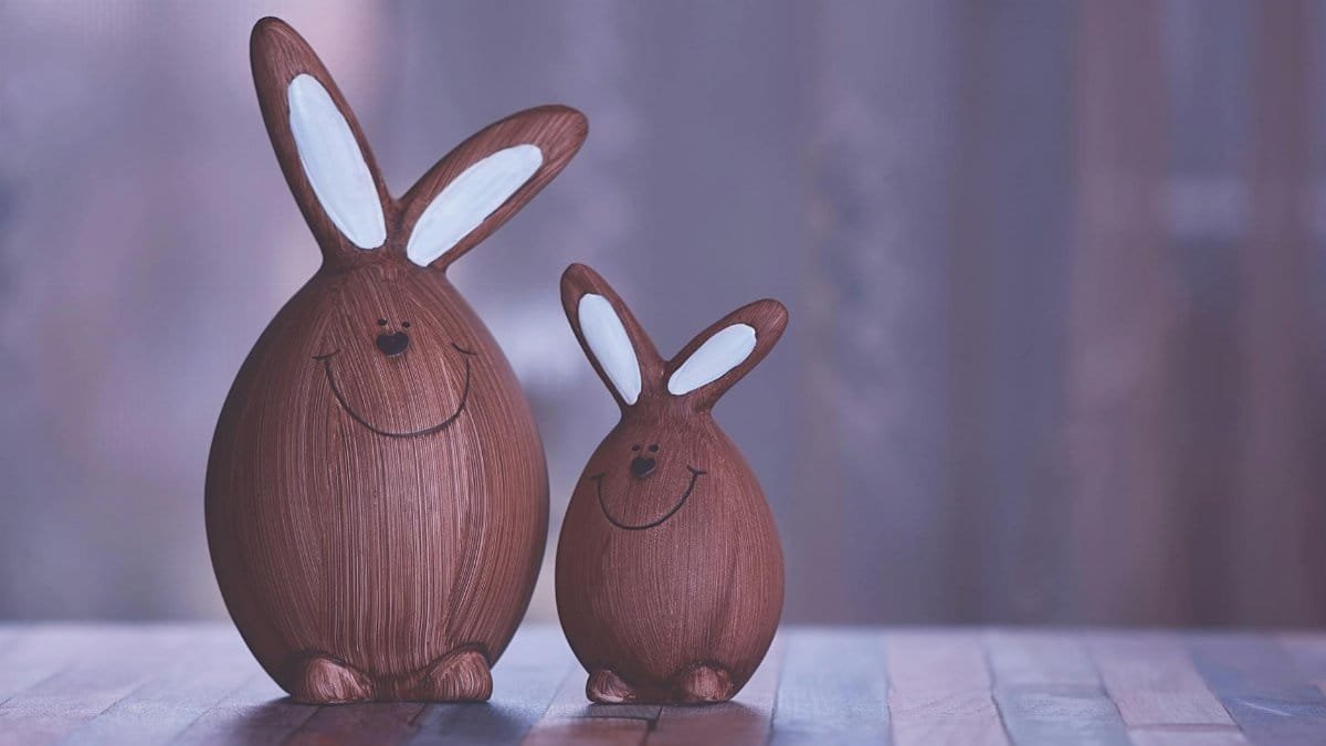 Two wooden Easter bunny figurines standing on a table with a soft focus background.