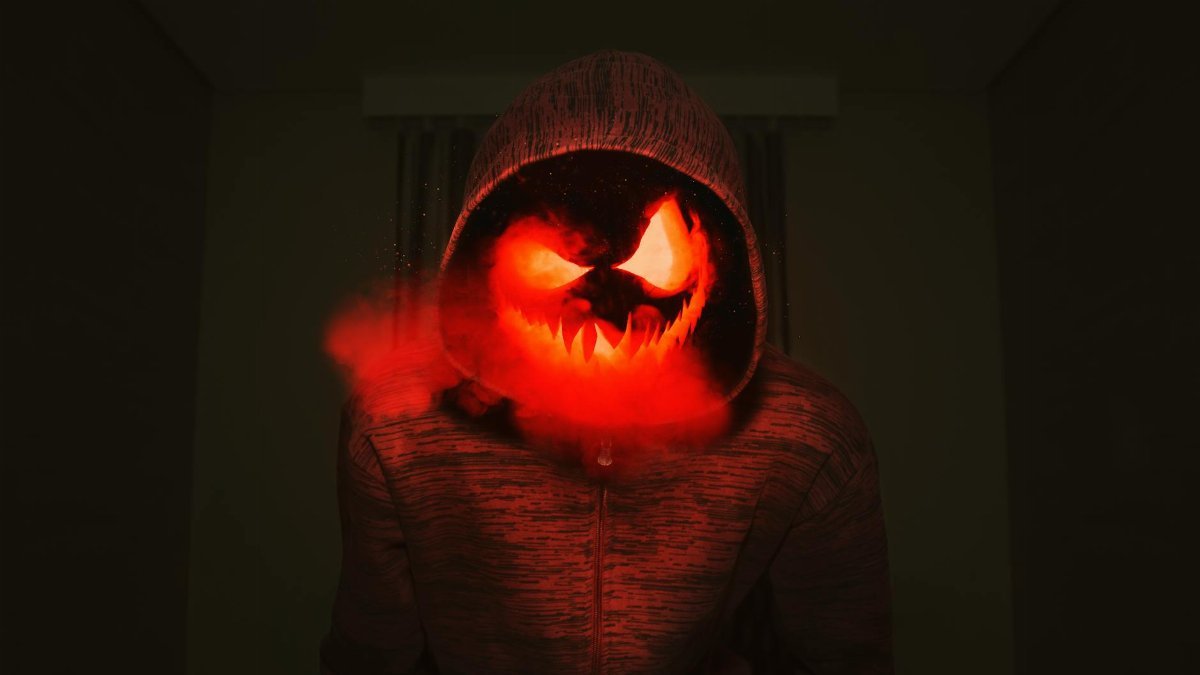 A spooky pumpkin head in a hoodie exudes a creepy Halloween vibe with red smoke.