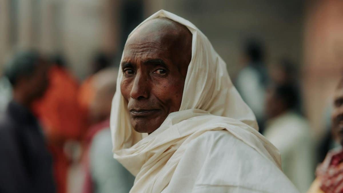 Elderly man in traditional attire, captured in a contemplative moment. Street scene.